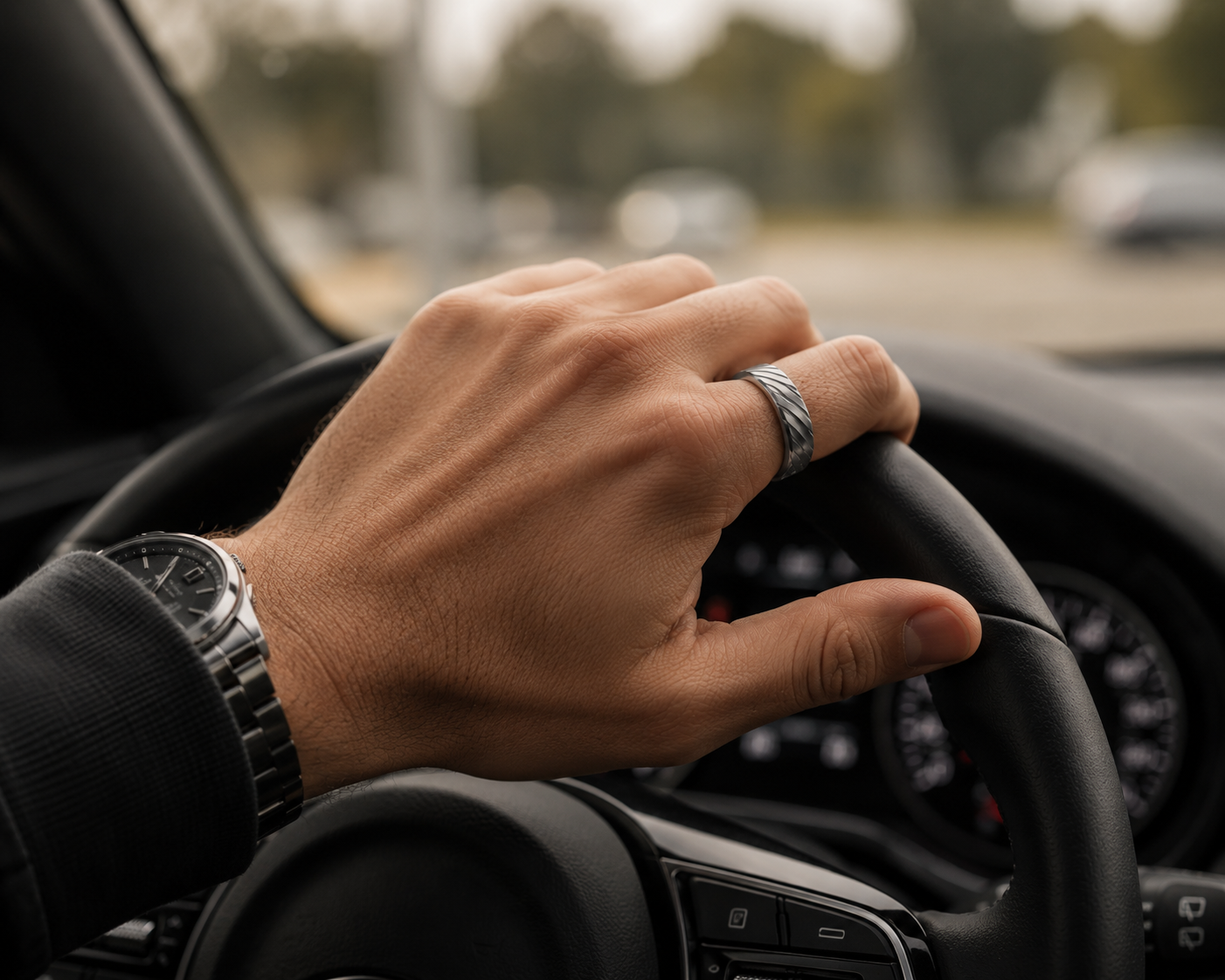 Hand am Lenkrad mit dem SKELVIA Smart Ring am Ringfinger und einer Armbanduhr am Handgelenk