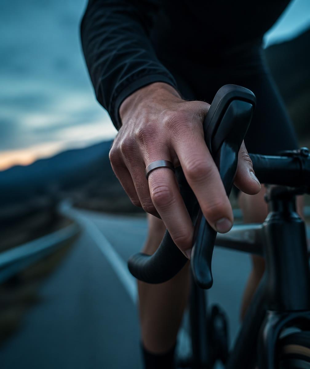Hand am Rennradlenker mit SKELVIA Smart Ring in der Dämmerung